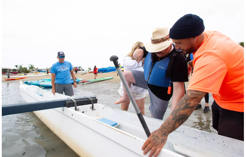 Volunteers with Makapo Aquatics show adults with developmental disabilities served by Project Independence how to paddle outrigger canoes. (Eric Licas)