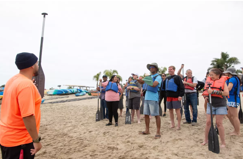 A volunteer with Makopo Aquatics gives adults with developmental disabilities and staff with Project Independence a crash course in outrigger paddling at the Newport Aquatic Center in Upper Newport Bay on Friday. (Eric Licas)